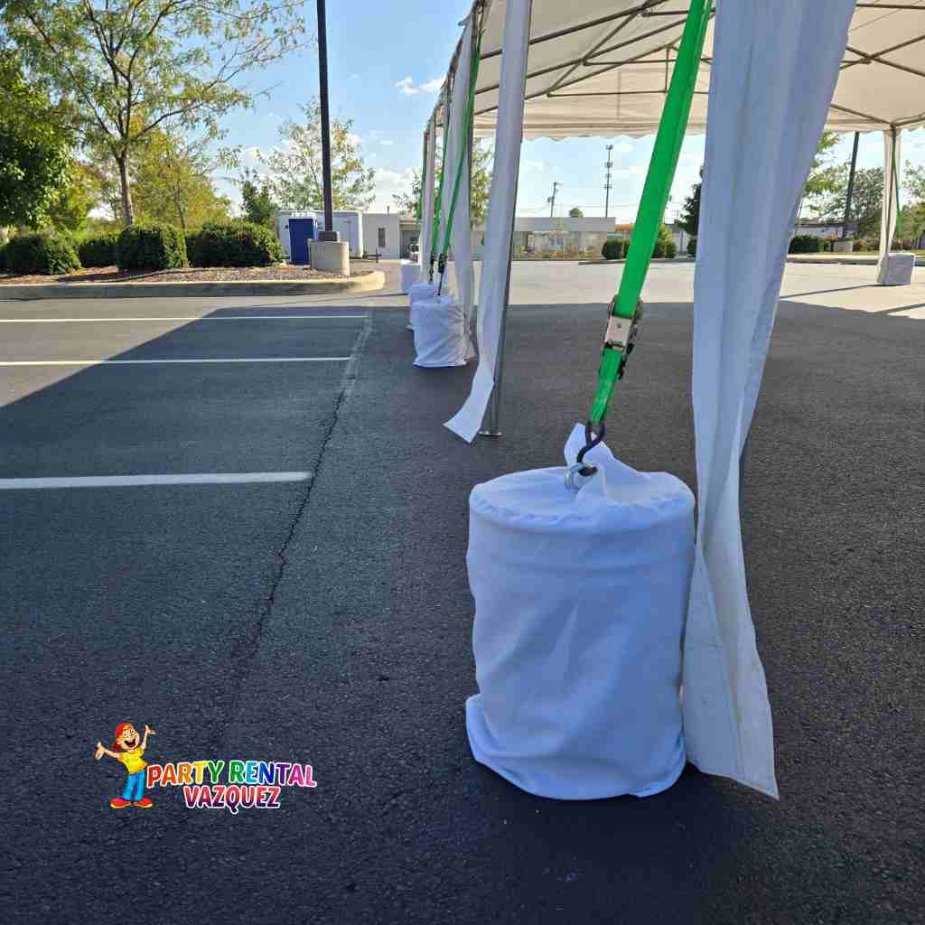 Concrete blocks securing a 13x27 PE tent at an outdoor event, stable anchoring system without stakes, ideal for party rentals in Columbus Indiana